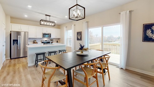dining area with black dining table and tan chairs next to sliding glass doors