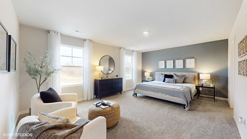 spacious primary bedroom with two windows that flood the room with natural light