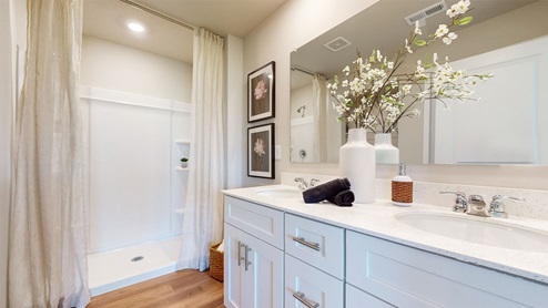 primary bathroom with large mirror and white cabinets