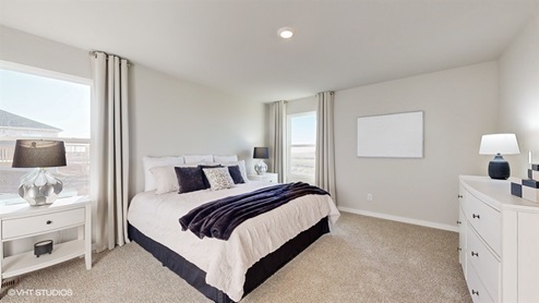 Primary bedroom in the Neuville with a king bed and white dresser