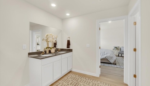 Master bathroom featuring double stinks and door leading into bedroom.