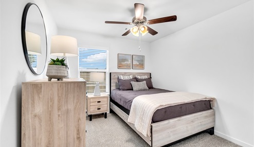 Spacious bedroom with white walls, carpet, one window and ceiling fan.