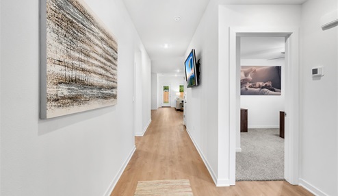 Entryway that leads into the open-concept living, kitchen and dining area with white walls and light floors.