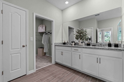 Master bathroom with double vanity, large wall mirror, cabinets and granite countertops.