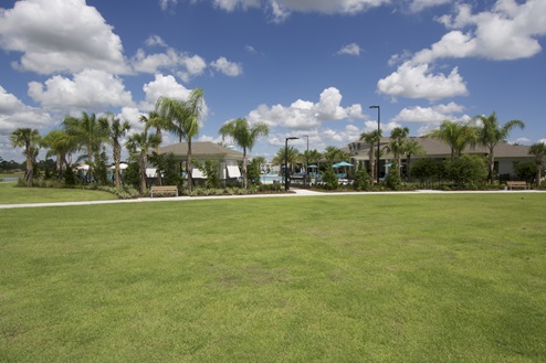 Clubhouse open and spacious outdoor area with grass overseeing gated access to pool.