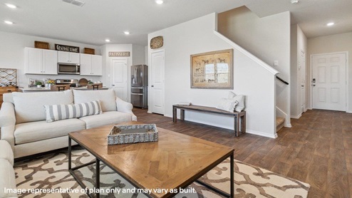 Open-concept living area with hard surface flooring facing spacious kitchen.