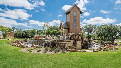 Bulverde Texas DR Horton Homes Copper Canyon New Construction Homes front entry with waterfall rocks pond and wooden waterwheel and tower