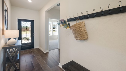 Bulverde Texas DR Horton Homes Copper Canyon Model Home Irvine floor plan 1796 square feet single story New Construction Homes front door entryway with hard surface floors entryway console table with table lamp and wicker storage mounted hooks on hallway wall and bench