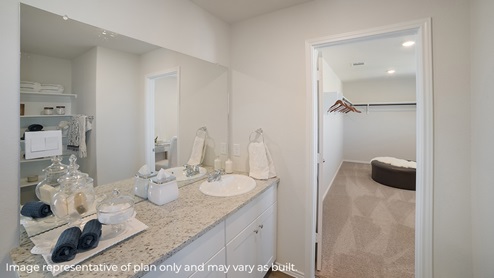 DR Horton Von Ormy Preserve at Medina the nicole floor plan 2473 square feet main ensuite bathroom with single vanity granite countertops white cabinets and doorway leading to oversized elongated walk in closet complete with carpet flooring and windows