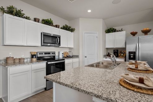 Rockbridge Model Home open-concept kitchen with granite countertops ad galley island with sink.