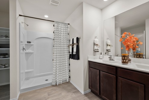 Rockbridge Model Home primary bathroom with dark cabinetry and ceramic tile shower surround.