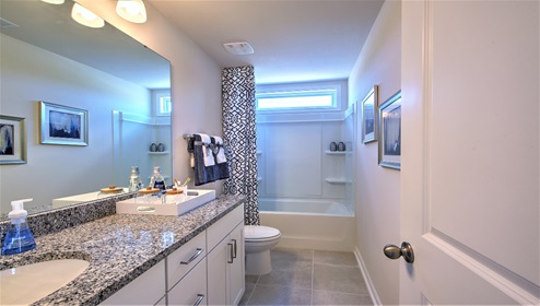 Bathroom with bathtub, white cabinets and large window