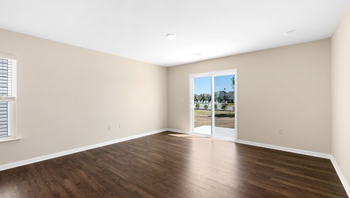 Open living room beside kitchen with windows and sliding glass back door. New home in Asheville, North Carolina