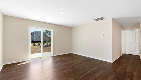 Open living room beside kitchen with windows and sliding glass back door. New home in Asheville, North Carolina