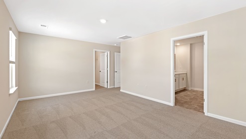 Primary bedroom with beige carpet and two large windows. New home in Asheville, North Carolina