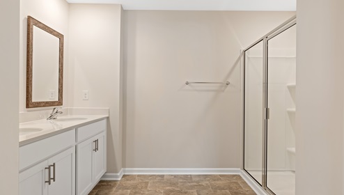 Primary bathroom with double sink vanity and standing glass door shower