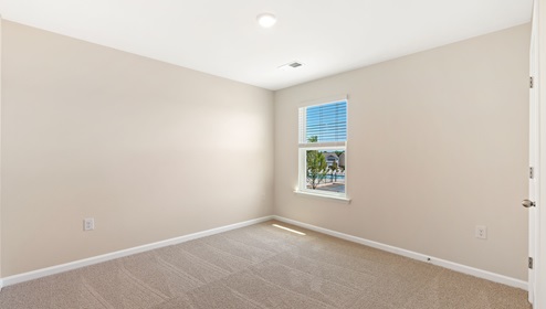 Carpeted bedroom with small window. New home in Asheville, North Carolina