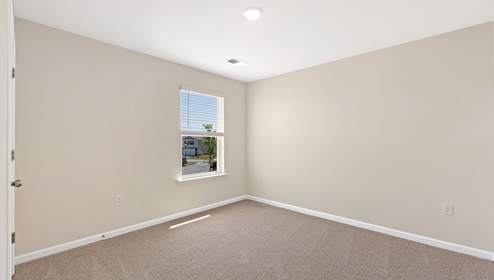 Carpeted bedroom with small window. New home in Asheville, North Carolina