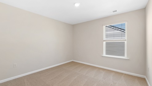 Carpeted bedroom with small window. New home in Asheville, North Carolina