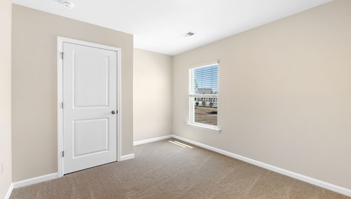 Carpeted bedroom with small window. New home in Asheville, North Carolina
