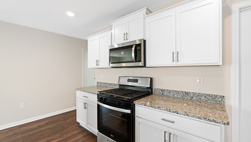 Kitchen and island with white cabinets, and stainless steel appliances. New home in Asheville, North Carolina