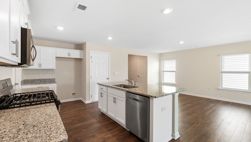 Kitchen and island with white cabinets, and stainless steel appliances. New home in Asheville, North Carolina