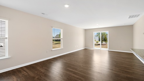 Open living room beside kitchen with windows and sliding glass back door. New home in Asheville, North Carolina