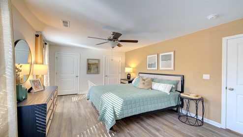 primary bedroom with vinyl flooring, ceiling fan and two large windows