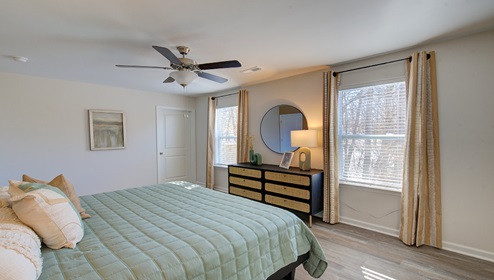 primary bedroom with vinyl flooring, ceiling fan and two large windows