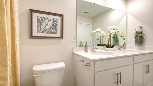 Bathroom with double sink vanity, white cabinets, and bathtub shower combination