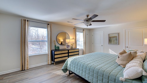 primary bedroom with vinyl flooring, ceiling fan and two large windows