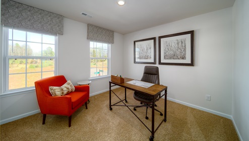 Carpeted bedroom with two large windows, being used as office