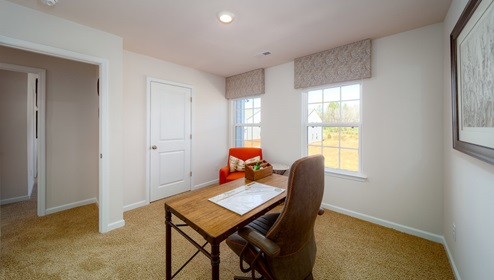 Carpeted bedroom with two large windows, being used as office