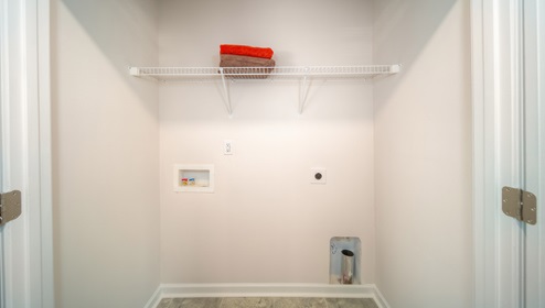Laundry room with built in storage and hanging racks above machine space