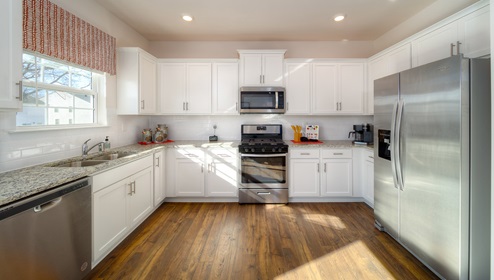 Kitchen with white cabinets, wood floors, and stainless steel appliances