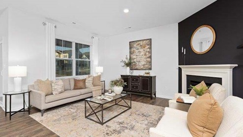 Modern open-concept living room with wood floors, and a fireplace, located beside kitchen