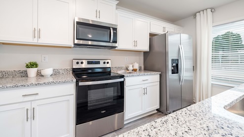Kitchen and island with white cabinets, granite countertops and stainless steel appliances
