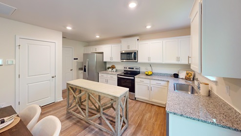 Kitchen and island with white cabinets, tile backsplash and stainless steel appliances