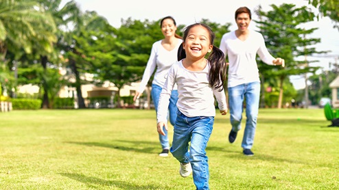 Happy Young Couple Running with Daughter Outside