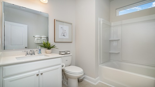 secondary bathroom with white cabinets and a shower tub combo