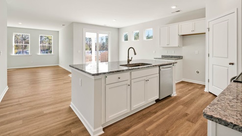 A large gourmet kitchen that features a large island, granite countertops, walk-in pantry, and stainless-steel appliances. Luxury Vinyl Plank flooring is included throughout the home, giving you a wood-like look with the durability to handle all your beach days .