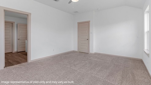 Spacious primary bedroom with carpet flooring and two bright windows.