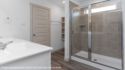 Primary bathroom with linen nook and walk-in shower.