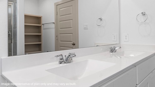Primary bathroom with double vanity and vinyl flooring.