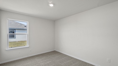 Secondary bedroom with grey carpet white walls and a large window providing natural light