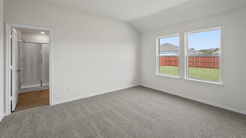 Primary bedroom located next to the living room with grey carpet and large windows facing the backyard