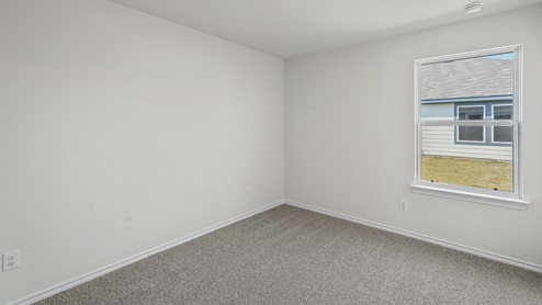 Secondary bedroom with grey carpet white walls and a large window providing natural light