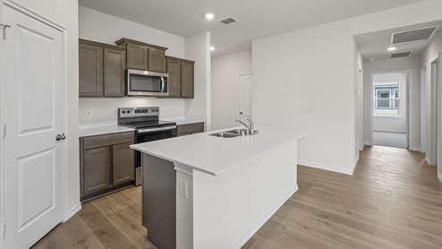 Kitchen area with hardwood floors dark cabinets and white countertops