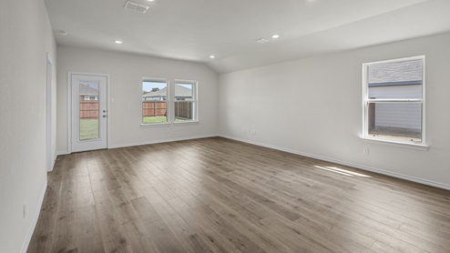 Open concept living area with hardwood floors and large windows facing the backyard providing natural light