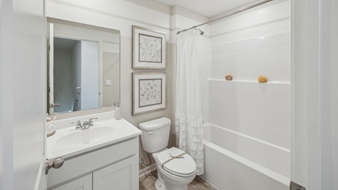 bathroom with a vanity sink and mirror above, toilet and a bathtub shower duo